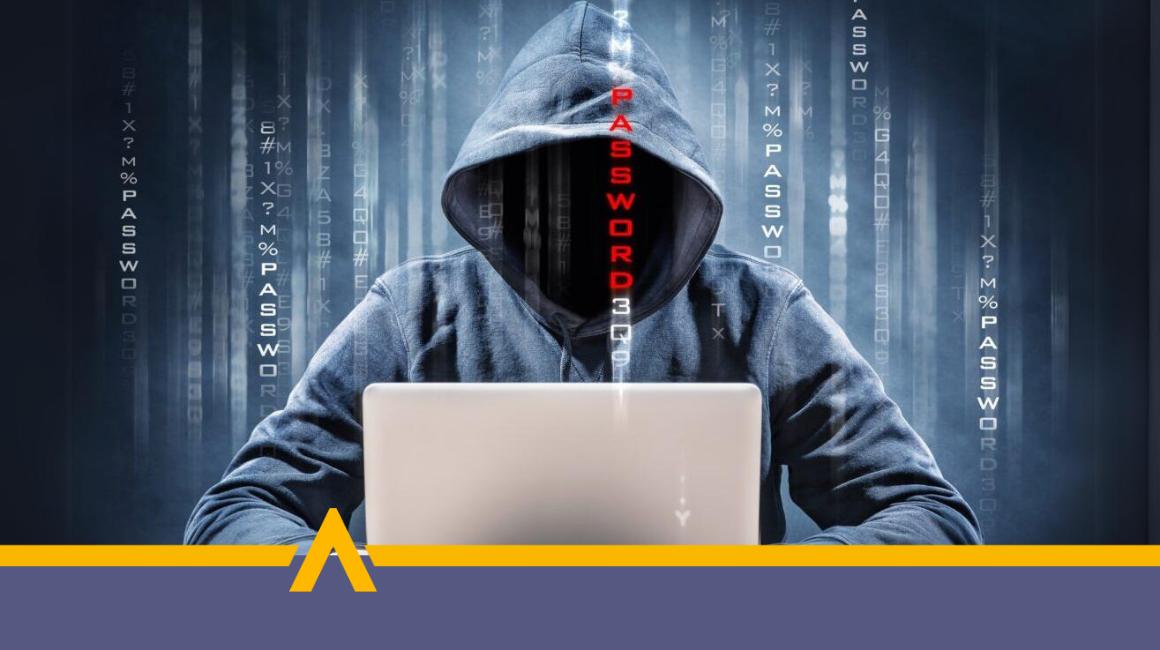 Haker w kapturze przy laptopie próbujący włamać się do systemu